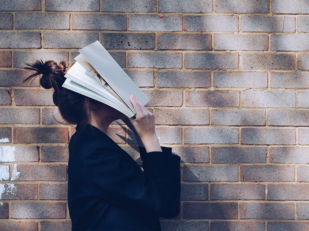 frustrated student covering face with book